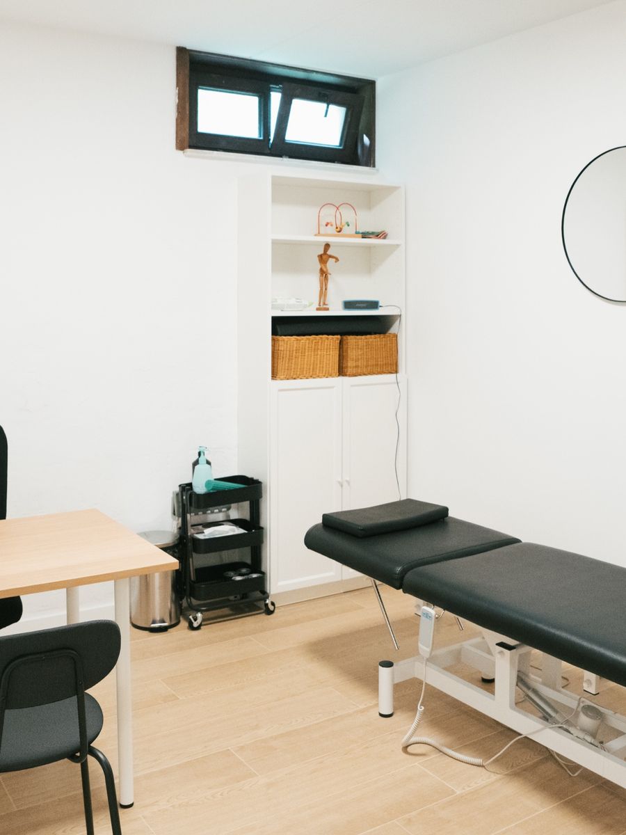 A treatment room with its treatment table, desk and mirror