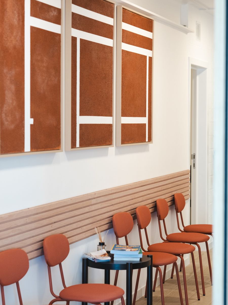 The waiting room, terracotta chairs lined up along light wood panelling
