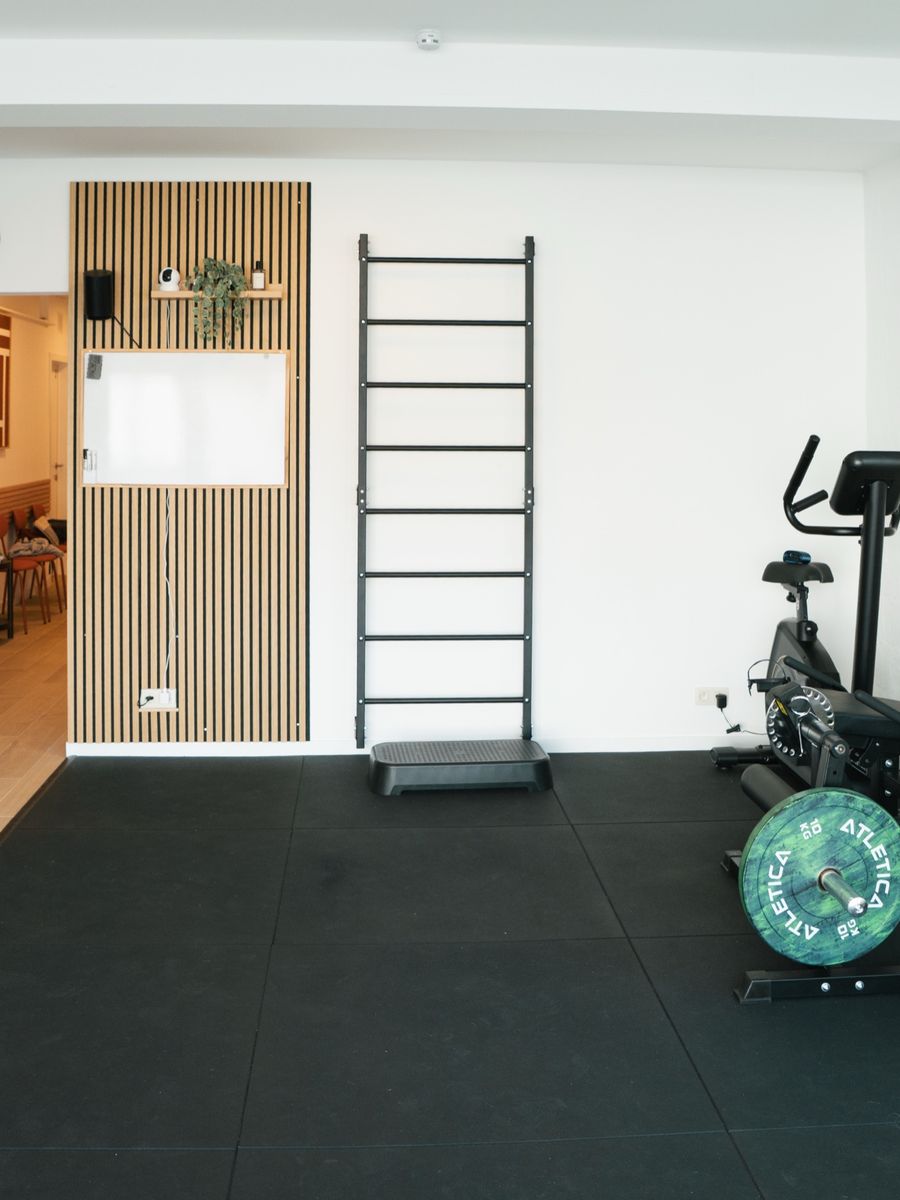 The rehabilitation room seen from the entrance: wall bars, exercise bike and floor mats